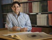 Joshua Sokol sitting at a desk in a library